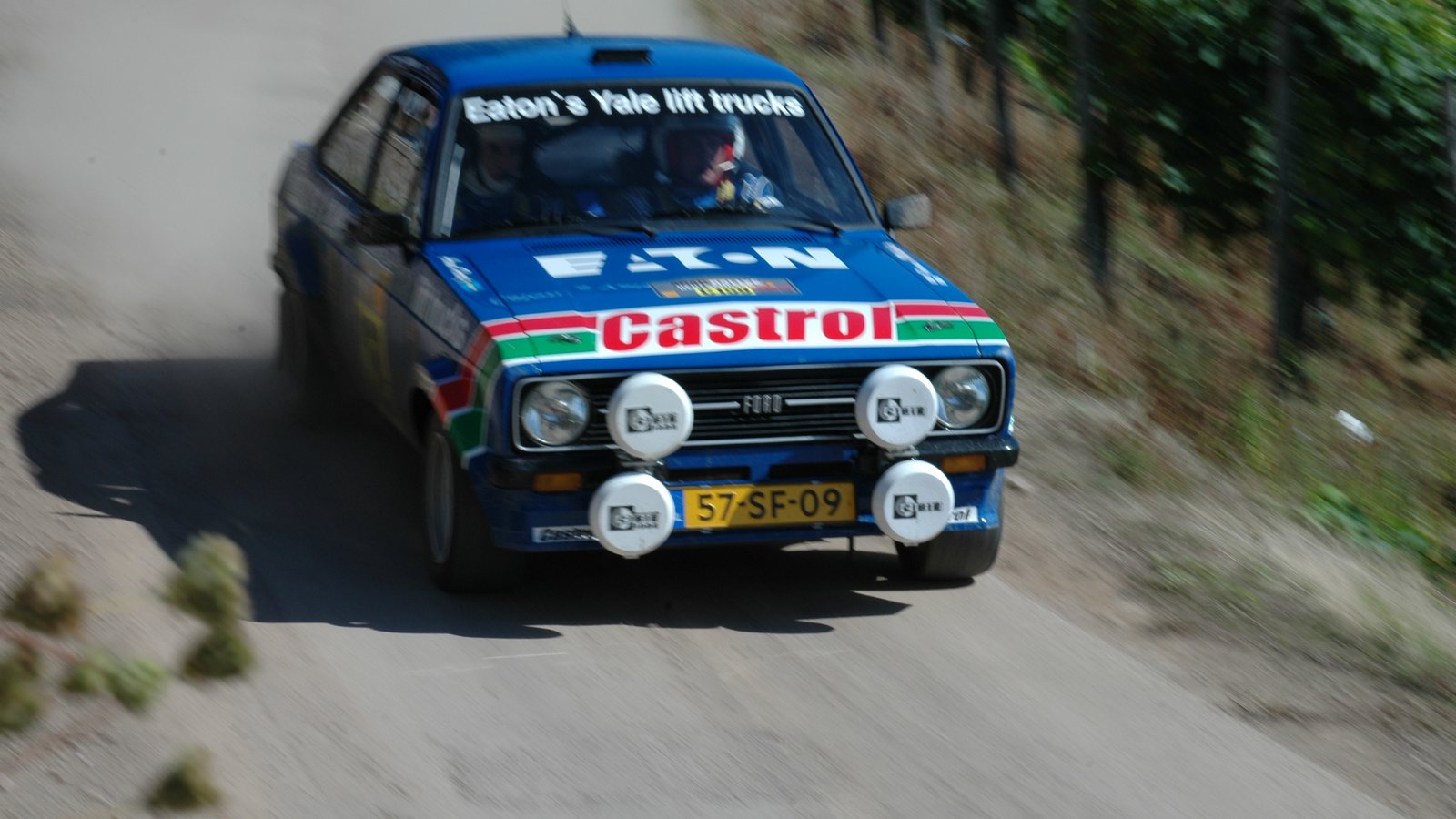 Blue Ford Escort Mk2 RS1800 rally car at speed on a tarmac stage